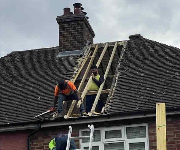 This is a photo of a roof repair being carried out. A section of the roof has been stripped and two roofers are replacing the rafters. Works being carried out by GKL Roofing Tickhill